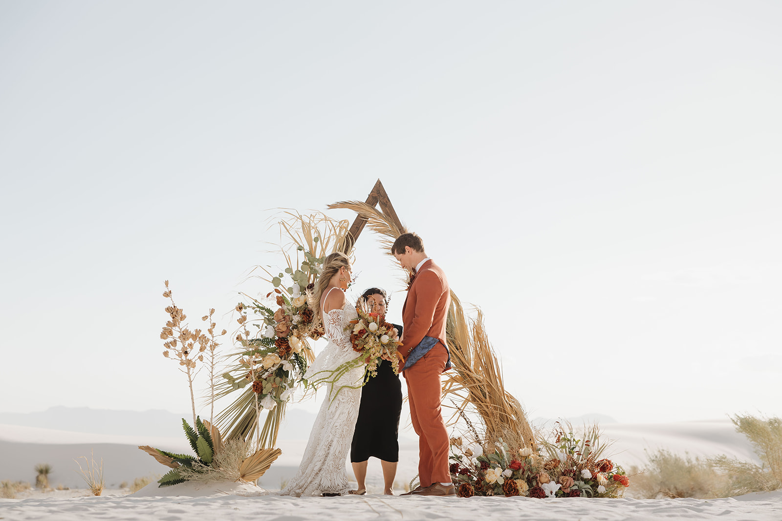 bride and groom pose in front of their wedding triangle/arch