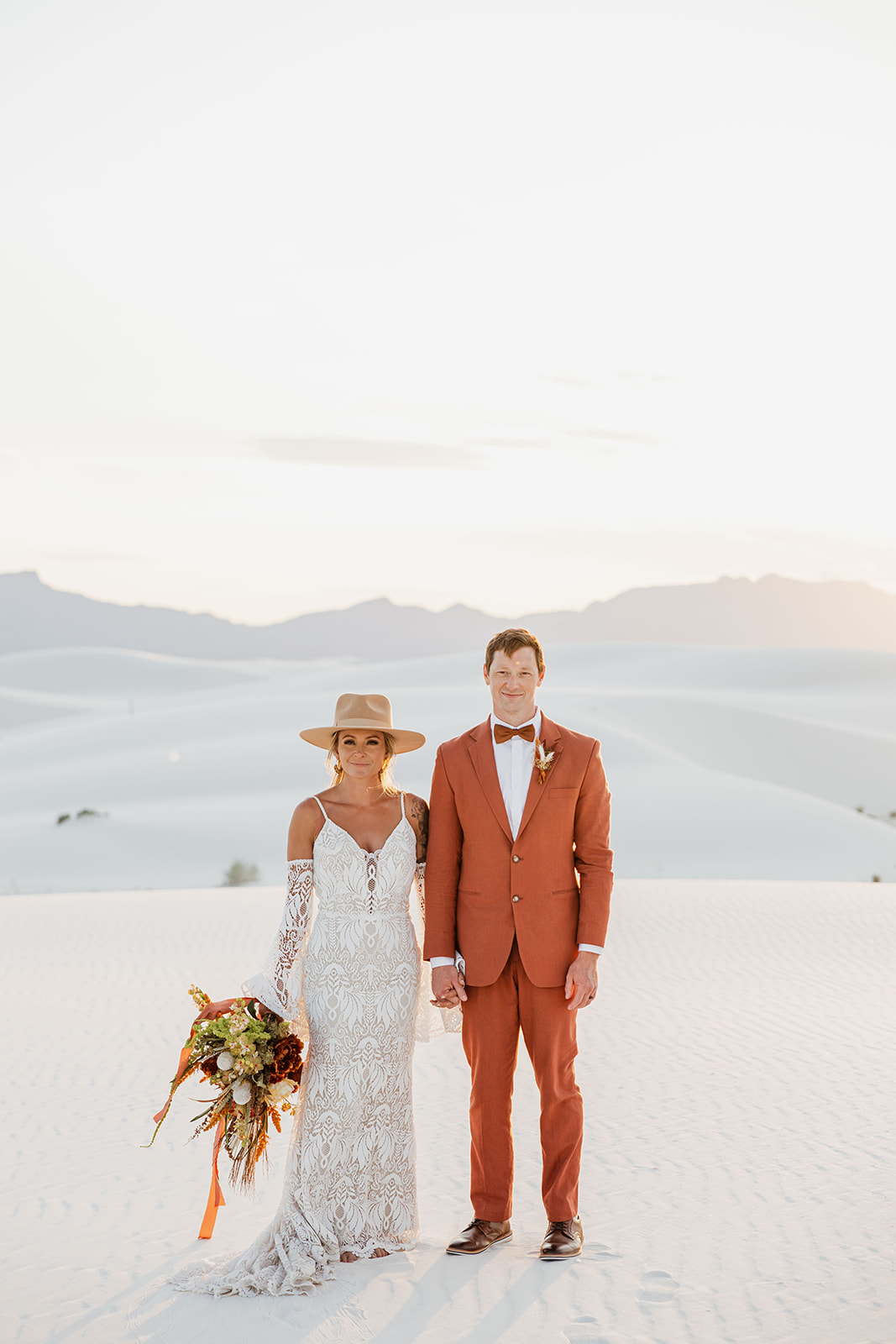 stunning bride and groom pose together with the dunes in background after their dreamy White Sands elopement day