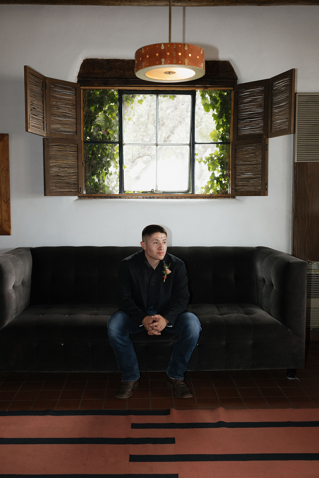 groom poses on the couch after his elegant wedding day